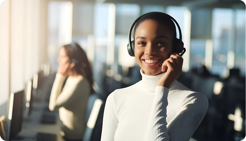 A smiling support agent in a headset at a busy contact centre